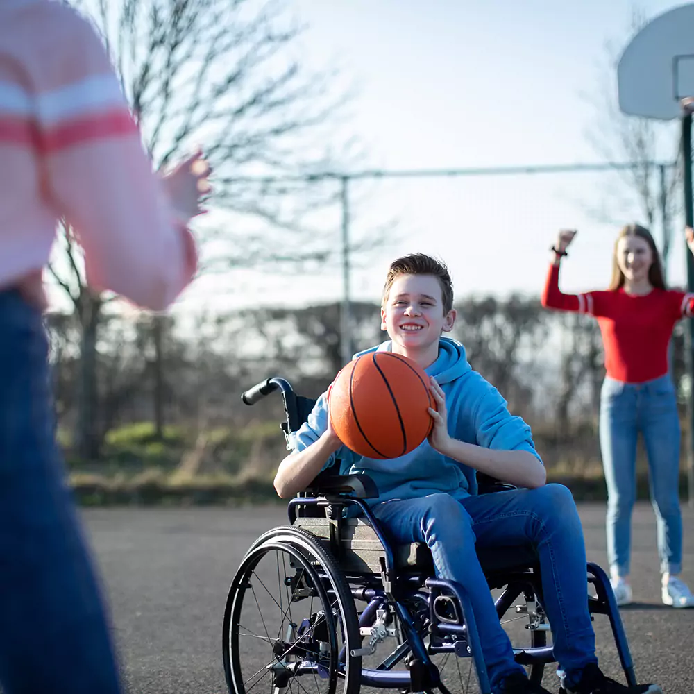 Disabled boy in wheelchair playing basketball