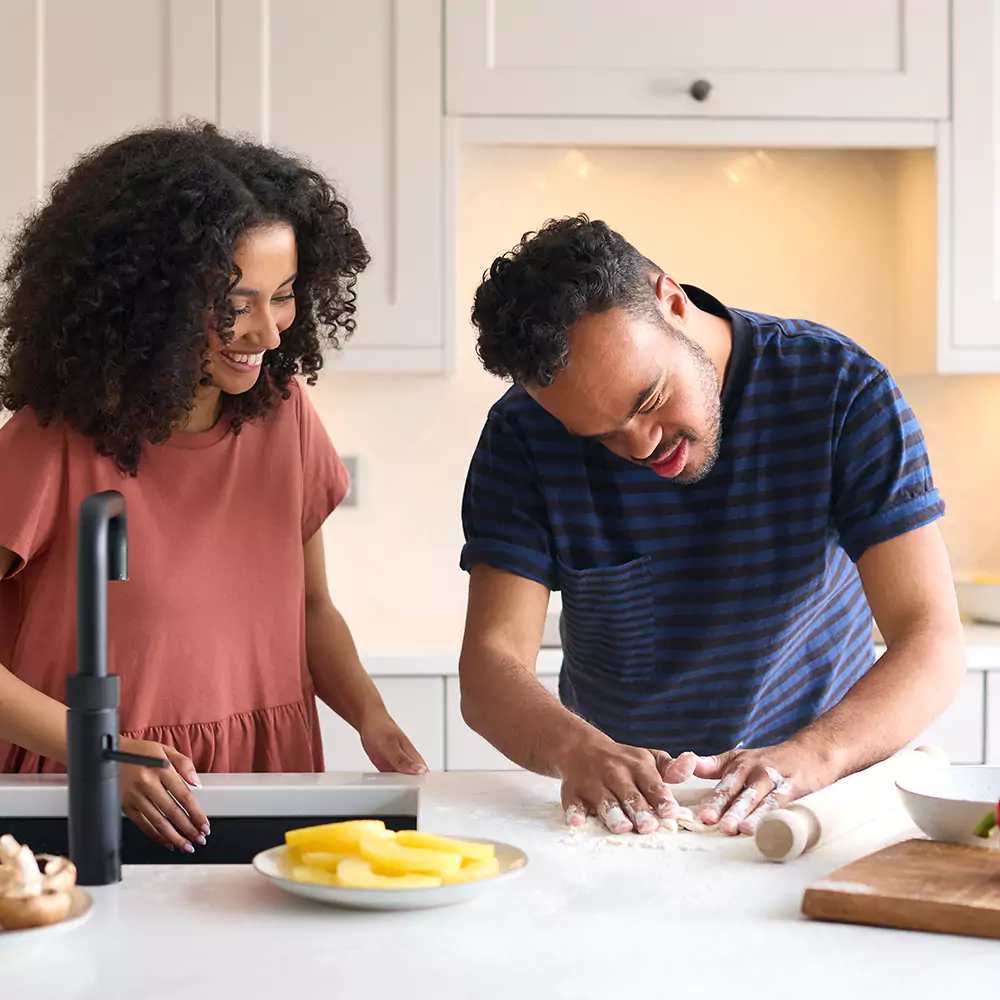 A down syndrome man and his care giver making pizza in the kitchen