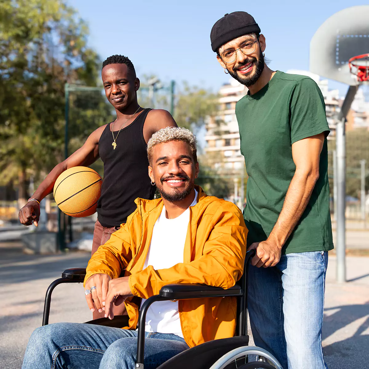 A man in a wheelchair being pushed outdoors with two of his friends