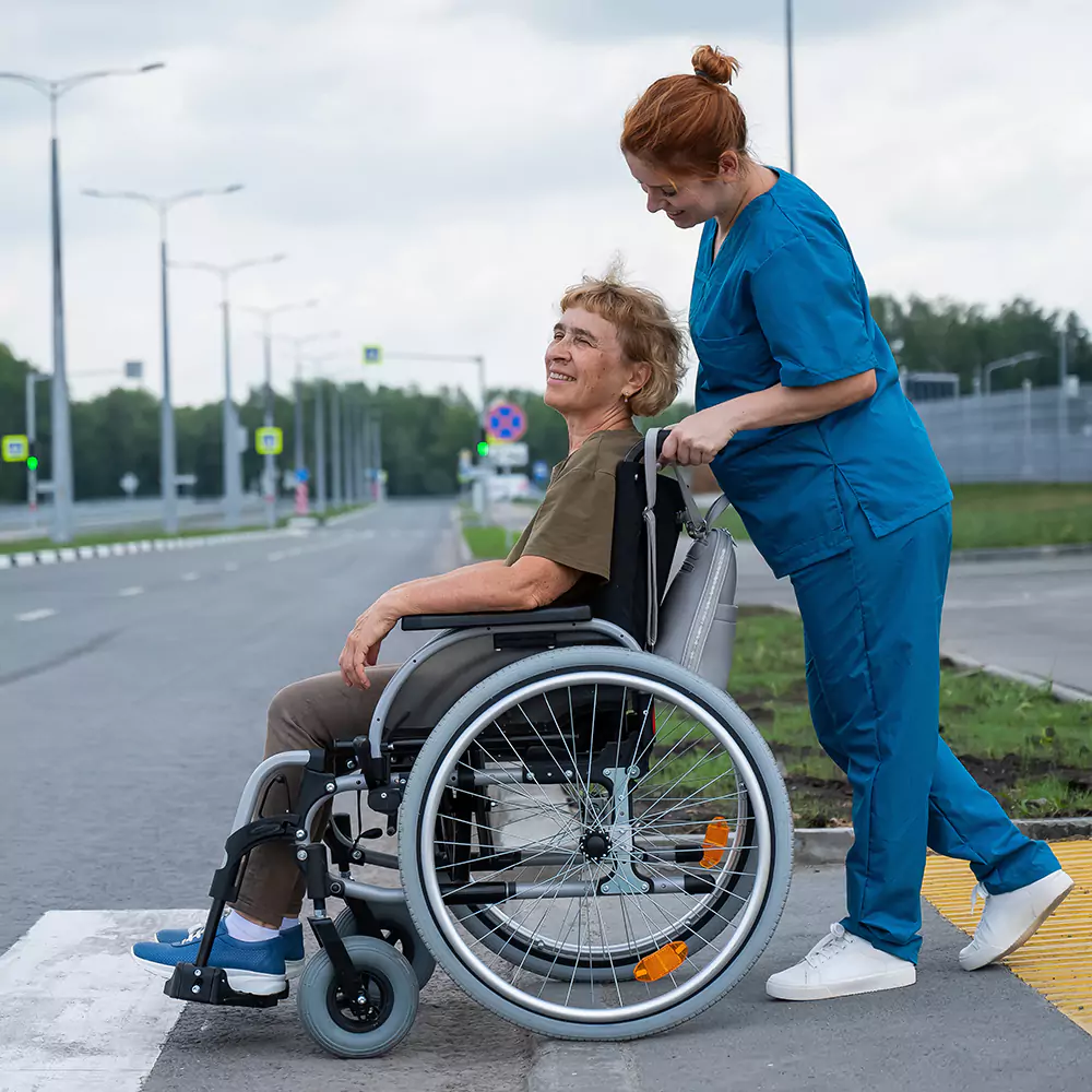 A nurse pushing a patient in a wheelchair across the street