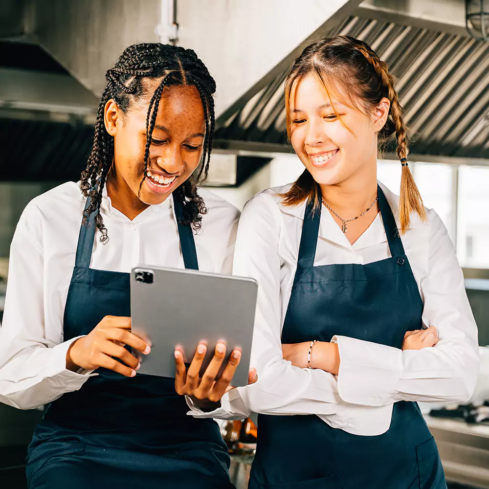 Two girls both looking at an ipad happily